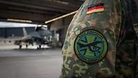 Das Patch Ein Aufnäher auf dem Ärmel eine Bundeswehruniform. Im Hintergrund ein Eurofighter