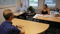 Ein Raum, mit Tischen an denen der Bewerbende dem Prüfoffizier und dem Psychologen gegenübersitzt. 