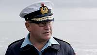 Ein Admiral in blauer Arbeitsuniform und mit weißer Schirmmütze.
