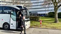 Die Menschen verlassen den Bus, der vor dem Gebäude hält, in dem das Assessment stattfindet.