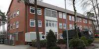 Rechteckiger Wohnblock mit spitzem Dach und einer mit rotem Backstein verkleideten Fassade