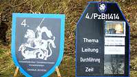 Auf der linken Seite ist ein Wappen mit einem Reiter, der einen Drachen tötet, auf der rechten eine Anzeigentafel.