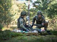 Sanitätsfeldwebel bei der Rettung Zwei Soldaten mit Kampfausrüstung versorgen einen Patienten