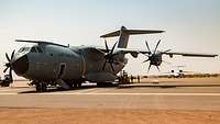 Ein Transportflugzeug A400M steht auf dem Flugplatz. Ein Gabelstapler und mehrere Soldaten laden Waren aus dem A400M