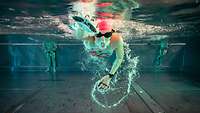 Ein Frau beim Schwimmen unter Wasser im Schwimmbecken