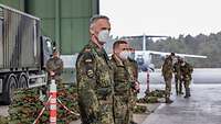 Ein Soldat steht neben anderen Soldaten in einer Halle und schaut in die Kamera