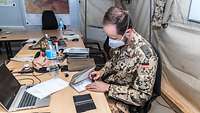Ein Soldat sitzt an einem Schreibtisch und setzt einen Stempel in ein Fahrzeugbegleitheft