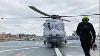 Am Deck eines Schieffes geht ein Soldat vom Hangar auf den gelandeten Sea Lion zu