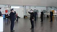 Ein Soldat in Marineuniform grüßt militärisch einen Soldaten in Luftwaffenuniform.