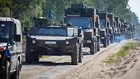 Militärische Fahrzeuge fahren hintereinander im Konvoi
