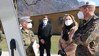 Zwei Soldaten und zwei Zivilisten mit Mund-Nasenschutz stehen neben einem Flipchart.