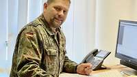 A soldier standing at his desk and looking into the camera