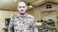 Ein Soldat steht in einem Zelt vor einem Tisch, auf dem zerlegte Waffen liegen