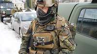 Ein deutscher JTAC-Offizier steht mit vollständiger Ausrüstung vor einer Reihe von Fahrzeugen