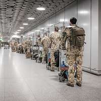 Viele Soldaten stehen mit ihrem Gepäck hintereinander in der Abfertigungshalle eines Flughafens