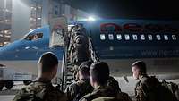 Das Boarding Mehrere Soldaten steigen in ein blau-weißes Flugzeug