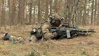 Ein Soldat liegt mit einem Gewehr in einer Stellung