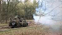 Ein offener grüner Geländewagen wird am Seil aus dem Moor im Wald gezogen. Der Nebel stammt von einer Nebelgranate.