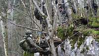 Ein Soldat auf einer Rettungstrage wird von seinen Kameraden an einem Felsen abgeseilt.