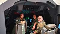 Drei Soldaten sitzen im Cockpit eines Simulators