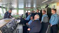 Mehrere Soldaten stehen einem vortragenden Soldaten auf der Brücke des Schiffs gegenüber 