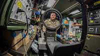 Blick durch ein Vergrößerungsglas auf einen Soldaten in einer Werkstatt mit elektrischen Apparaten