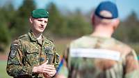 Ein Soldat spricht mit einem zweiten, der im T-Shirt und mit Basecap vor ihm steht.