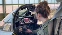 Jana T. beim Check der Instrumente im Cockpit über die Schulter fotografiert.
