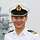 Portrait picture of a naval officer with a white uniform shirt and a white military cap.
