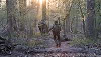 Zwei Soldaten rennen durch den Wald zu ihren Stellungen.