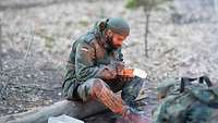 Ein Soldat sitzt am Lagerfeuer und isst eine Mahlzeit aus dem EPA.