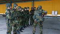 Ein Soldat zeigt etwas mit einer Pistole vor und andere Soldatinnen und Soldaten beobachten dies genau.