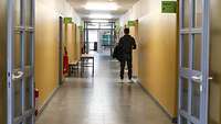 Eine Person steht im Gang eines Gebäudes und wartet vor einem Büro.