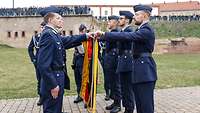 Mehrere Soldaten stehen nebeneinander und halten jeweils eine Hand an die Truppenfahne. Sie legen ihren Eid bzw. ihr Gelöbnis ab