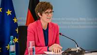 Bundesministerin der Verteidigung sitzt vor einem Mikrofon und hält eine Rede