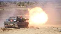 Ein Leopard 2A6 Kampfpanzer schießt und es tritt ein großer Feuerball aus seiner Kanone aus