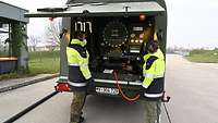 Zwei POL-Soldaten stehen hinten am Flugfeldtankwagen.