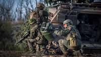 Aus der offenen Heckklappe eines Schützenpanzers stürmen drei Soldaten.