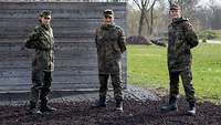 Drei Soldaten stehen vor einer Holzwand