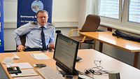 Ein Soldat in Uniform sitzt in einem Besprechungsraum beim Onlinemeeting