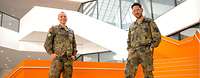 Zwei Soldaten stehen auf einer Treppe und lächeln in die Kamera