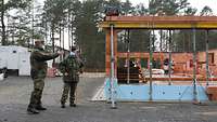 Ein Gebäude-Rohbau, daneben zwei Soldaten