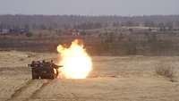 Schuss beim Rückwärtsfahren Ein Leopard 2A6 fährt auf der Schießbahn. Aus dem Kanonenrohr schlägt nach der Schussabgabe ein Feuerball