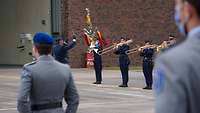 Musikalische Begleitung Blechblasmusiker spielen; im Vordergrund zwei Soldaten in Dienstanzug und mit blauem Barrett.