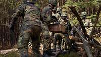 Mehrere Soldaten mit Mund- und Nasenschutz überwinden ein Hindernis in Teamarbeit
