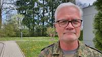 Portrait Portraitbild eines Mannes, grauhaarig mit einer Brille, im Hintergrund ist eine Wiese zu sehen
