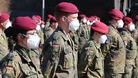 Soldaten in grüner Uniform stehen in Formation nebeneinander auf einem Platz. 