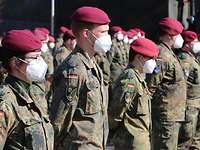 Soldaten in grüner Uniform stehen in Formation nebeneinander auf einem Platz. 