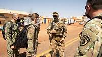 Soldaten und eine Soldatin verschiedener Nationen stehen im Halbkreis und besprechen sich