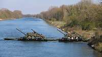 Auf einer Fähre auf der Donau stehen zwei Gefechtsfahrzeuge.